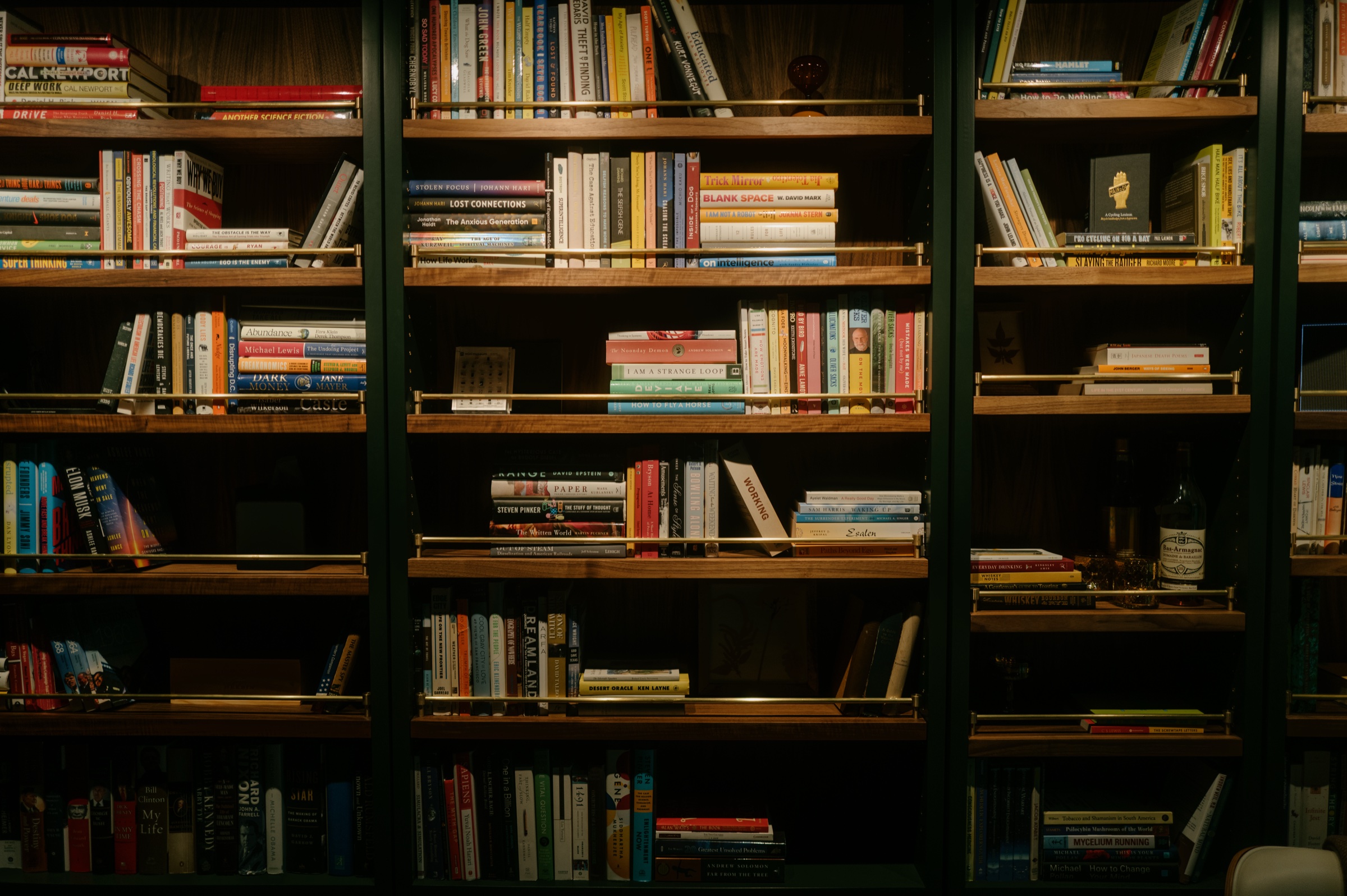Walnut bookshelves with brass rails, full of books